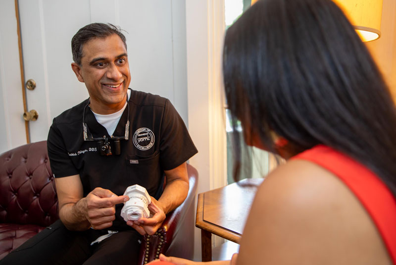 dr palayam showing implant model to patient